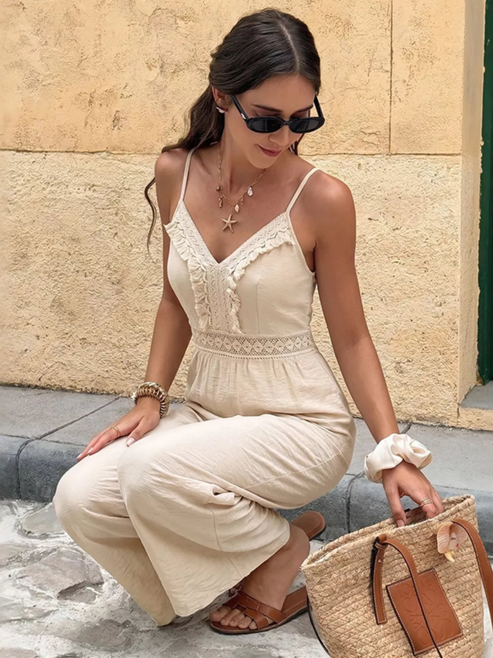 Lace-trimmed spaghetti strap romper in cream with cutout detail and wide legs.