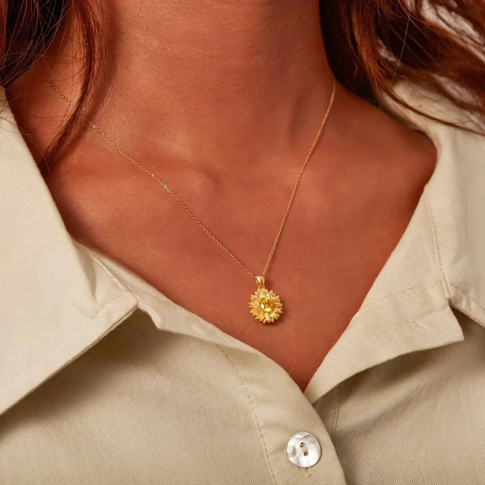 Gold sunflower pendant necklace with yellow gemstone detail on a delicate chain.