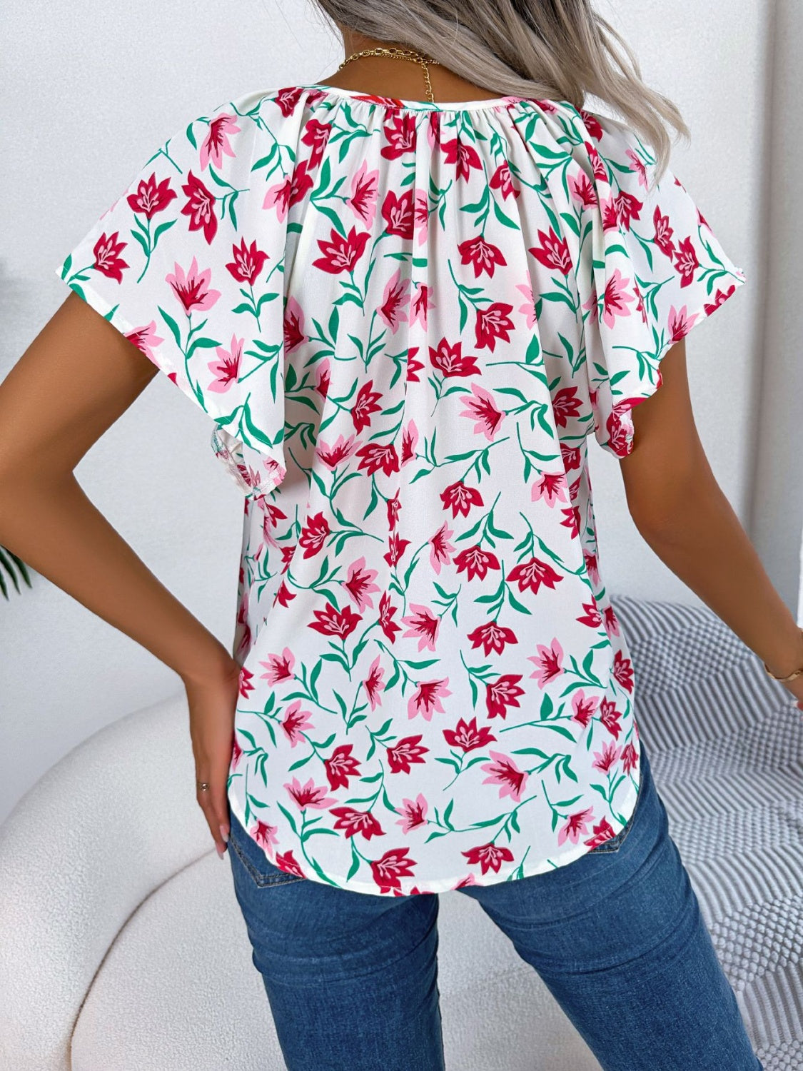 White floral ruffle sleeve tie-neck blouse with red and pink flowers.