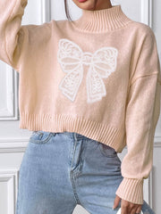 Blush pink knit turtleneck sweater with white lace bow appliqué detail.
