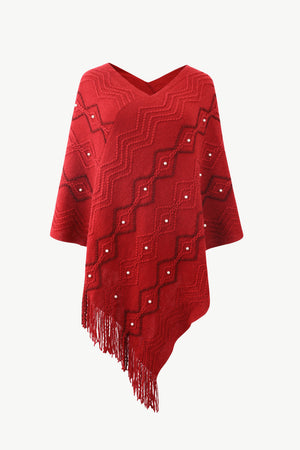 Red knit poncho with geometric pattern, pearl embellishments, and fringe detail.
