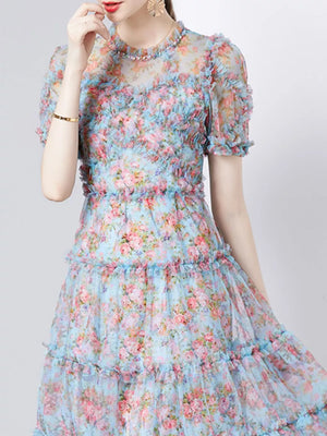 Ruffled floral dress with sheer neckline and short sleeves, tiered skirt.