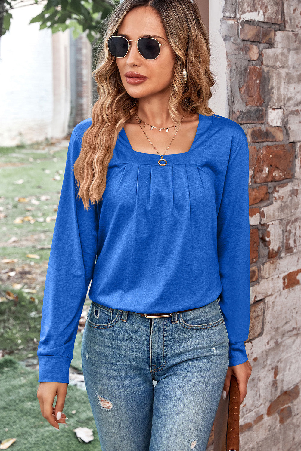 Blue long sleeve top with square neckline and pleated detail.