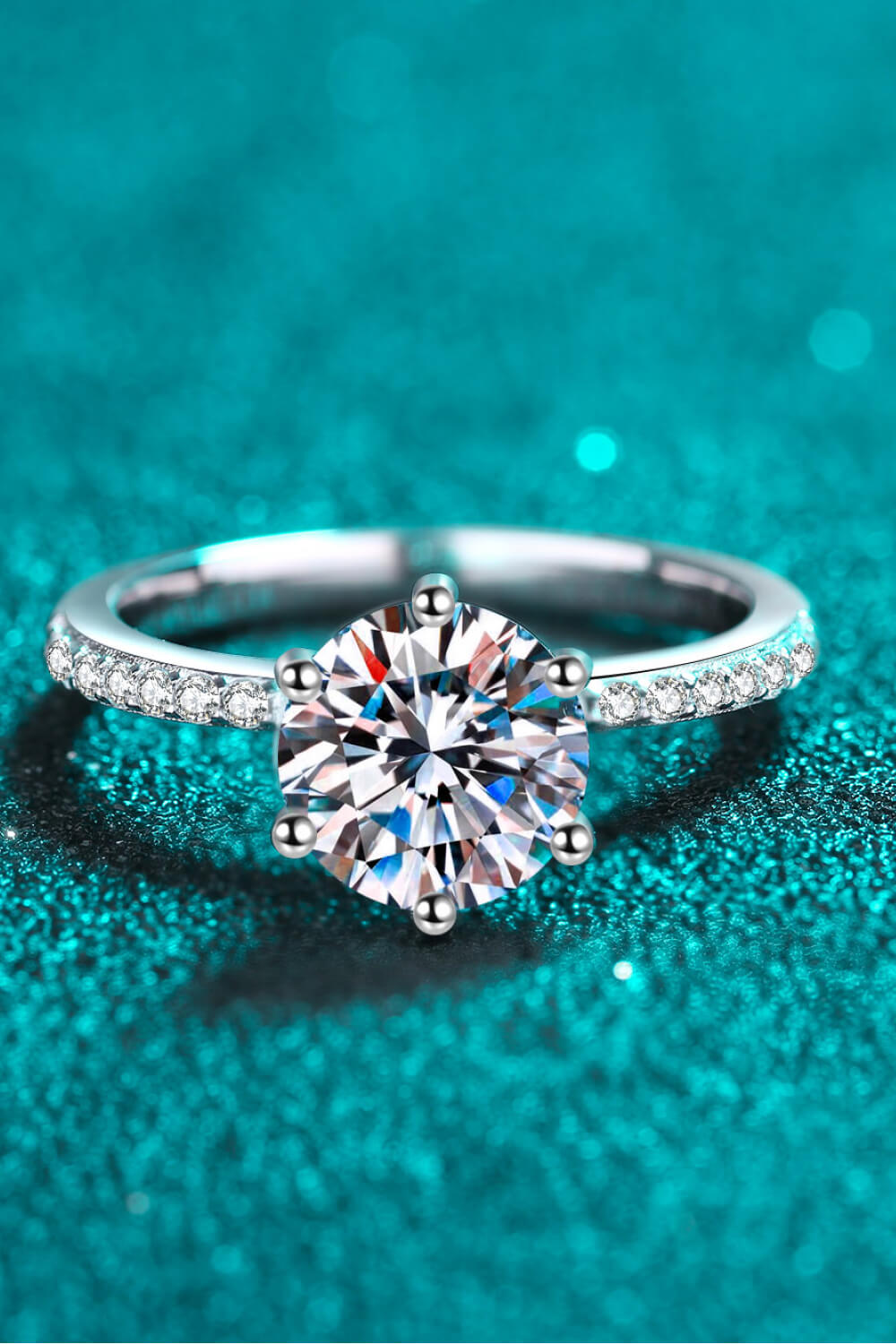 Silver moissanite ring with a round-cut center stone and pave band.