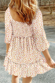 Floral smocked mini dress with tiered ruffles and 3/4 sleeves in a beige floral print.