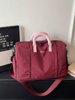 Burgundy nylon travel duffel bag with padded handles and detachable strap