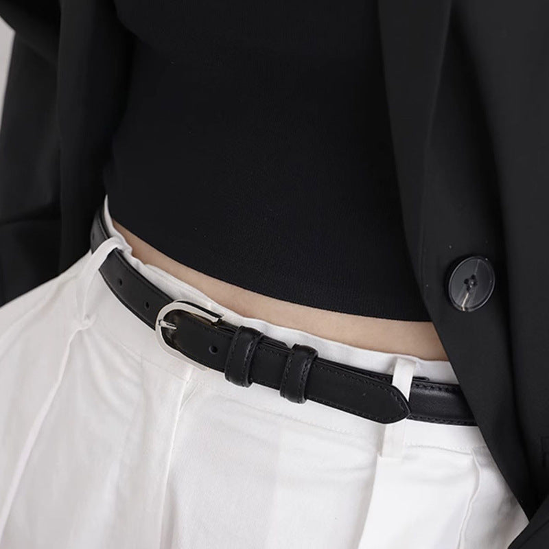 Skinny black leather belt with silver buckle, styled with a black top and white pants.