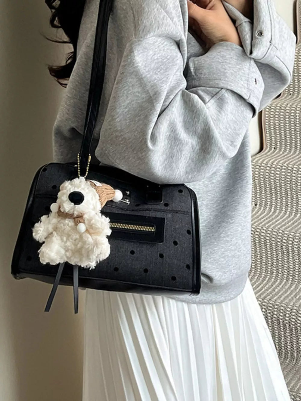 Black polka dot shoulder bag with a fluffy dog charm and gold hardware.