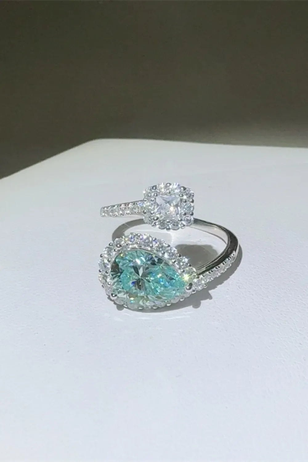Turquoise pear-cut moissanite bypass ring with halo and square halo ring.