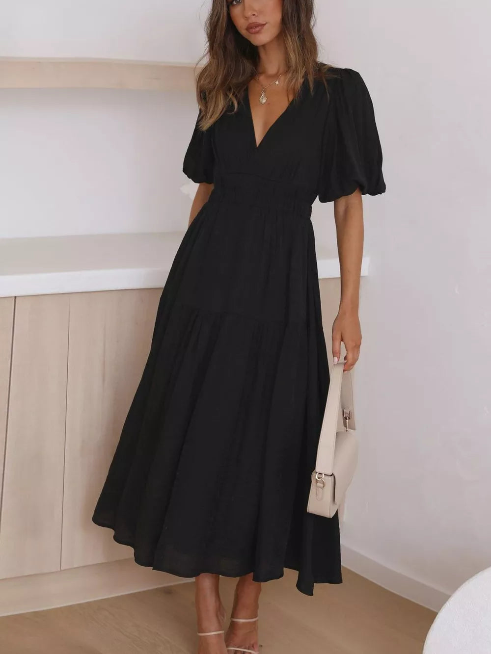 Black midi dress with V-neck, puff sleeves, smocked waist, and tiered skirt.