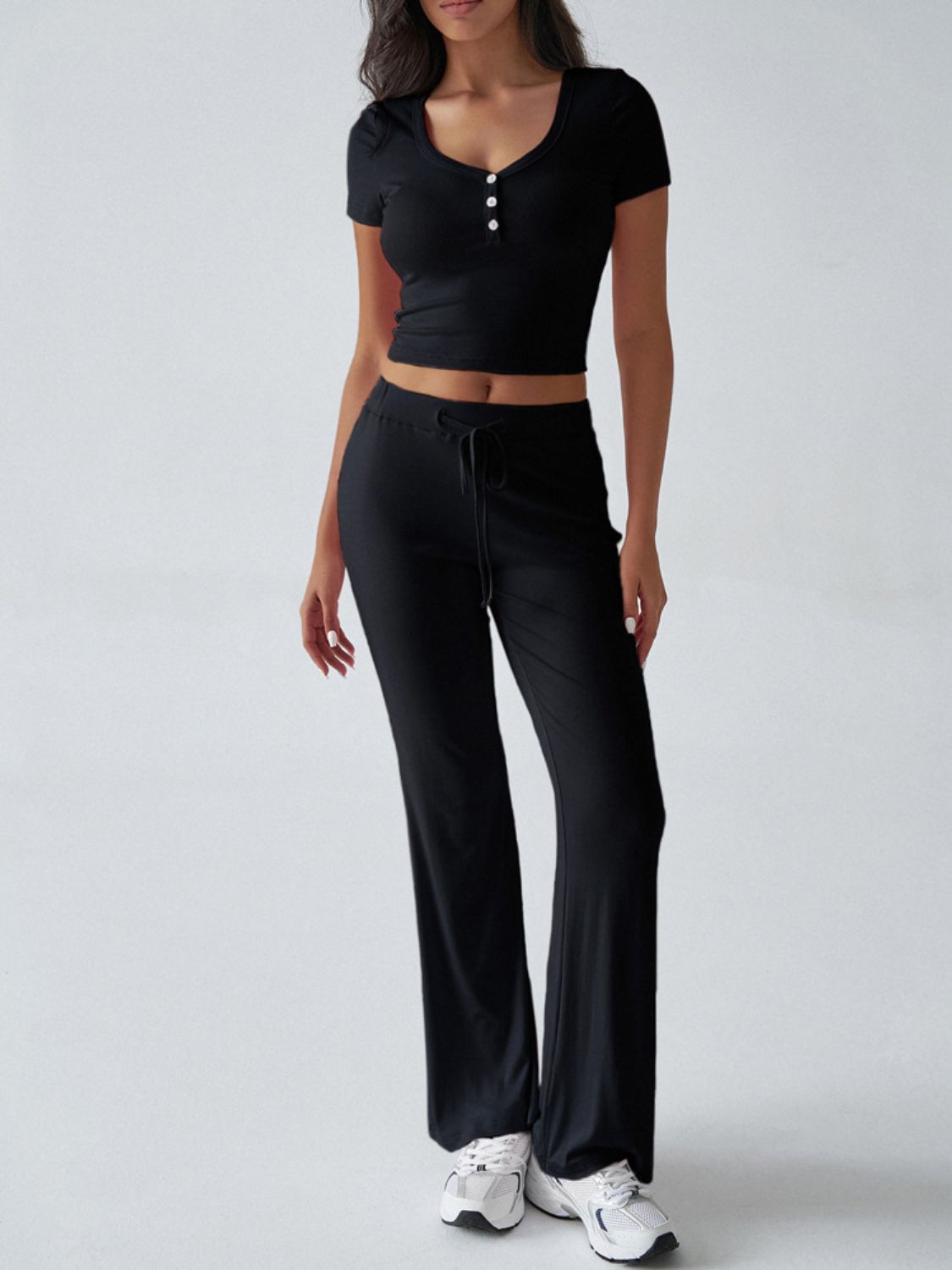 Black button-front crop top with short sleeves and flared lounge pants with drawstring waist.