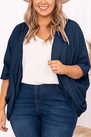 Dark blue ribbed batwing cardigan with drape front, worn over a white v-neck top.
