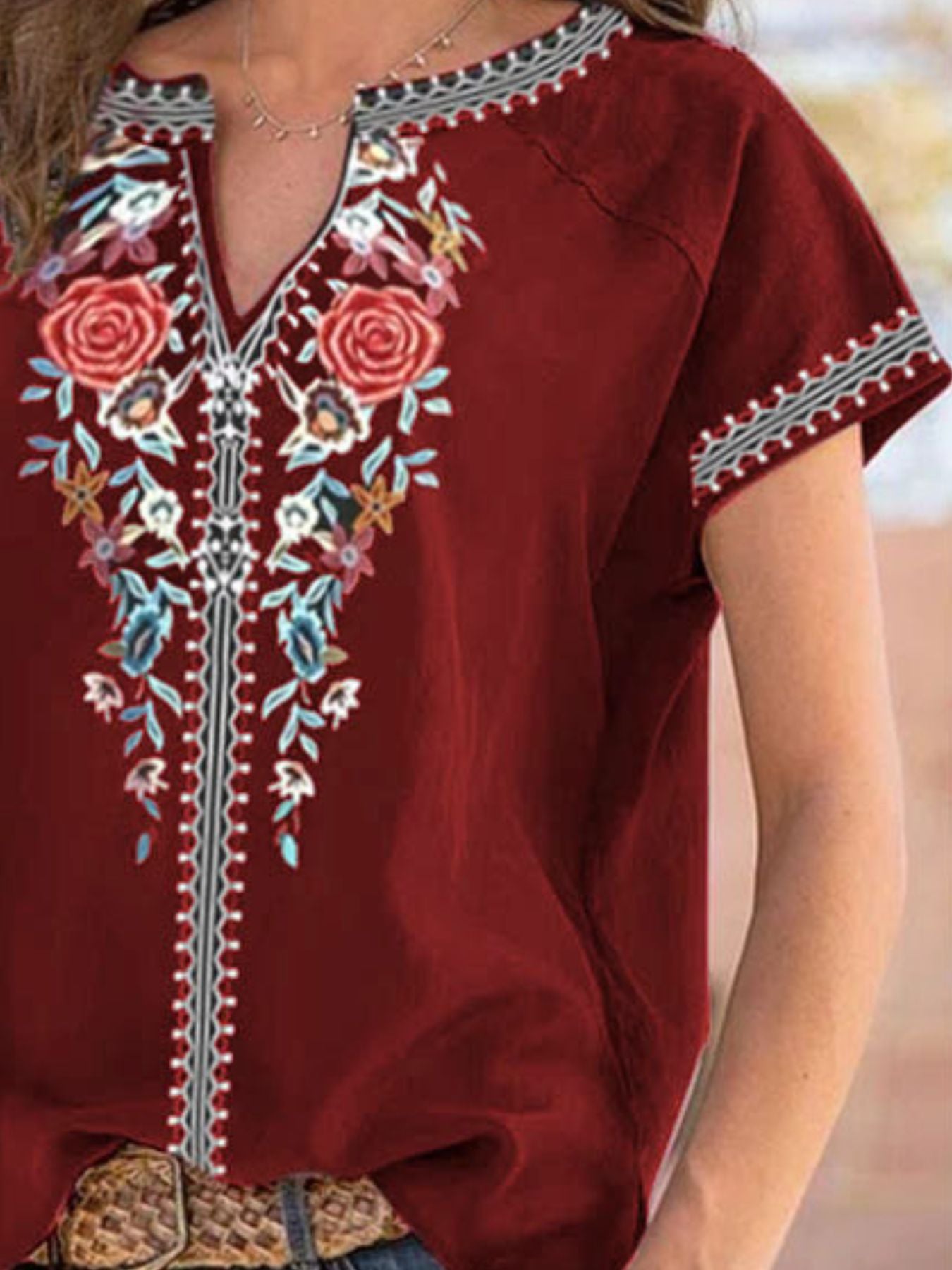 Burgundy floral embroidered notched blouse with short sleeves and decorative trim.