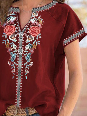 Burgundy floral embroidered notched blouse with short sleeves and decorative trim.