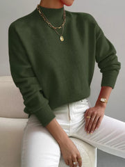 Army green mock neck knit sweater with dropped shoulders, styled with white pants and gold jewelry.