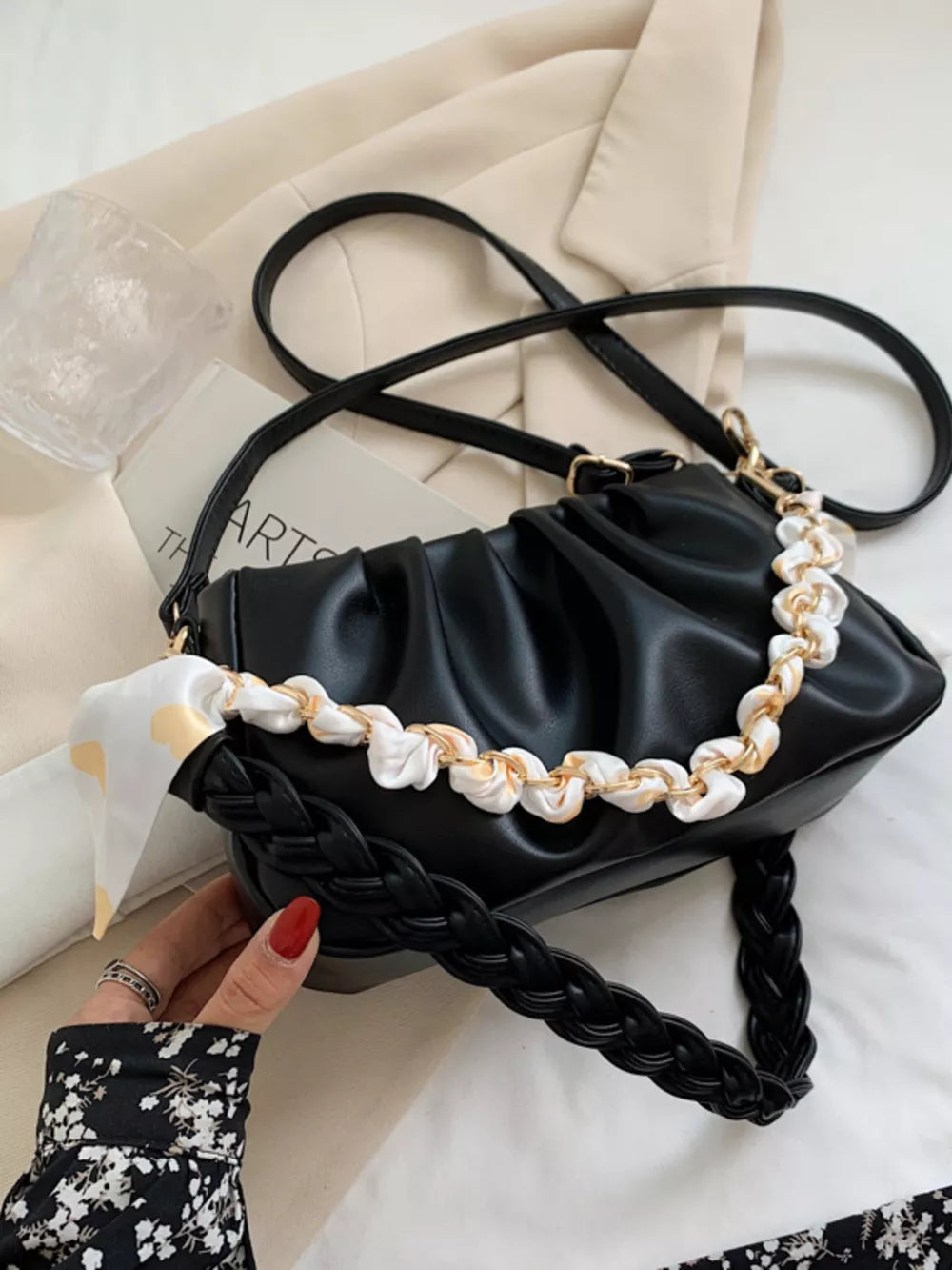 Black ruched mini shoulder bag with braided strap and decorative chain detail.