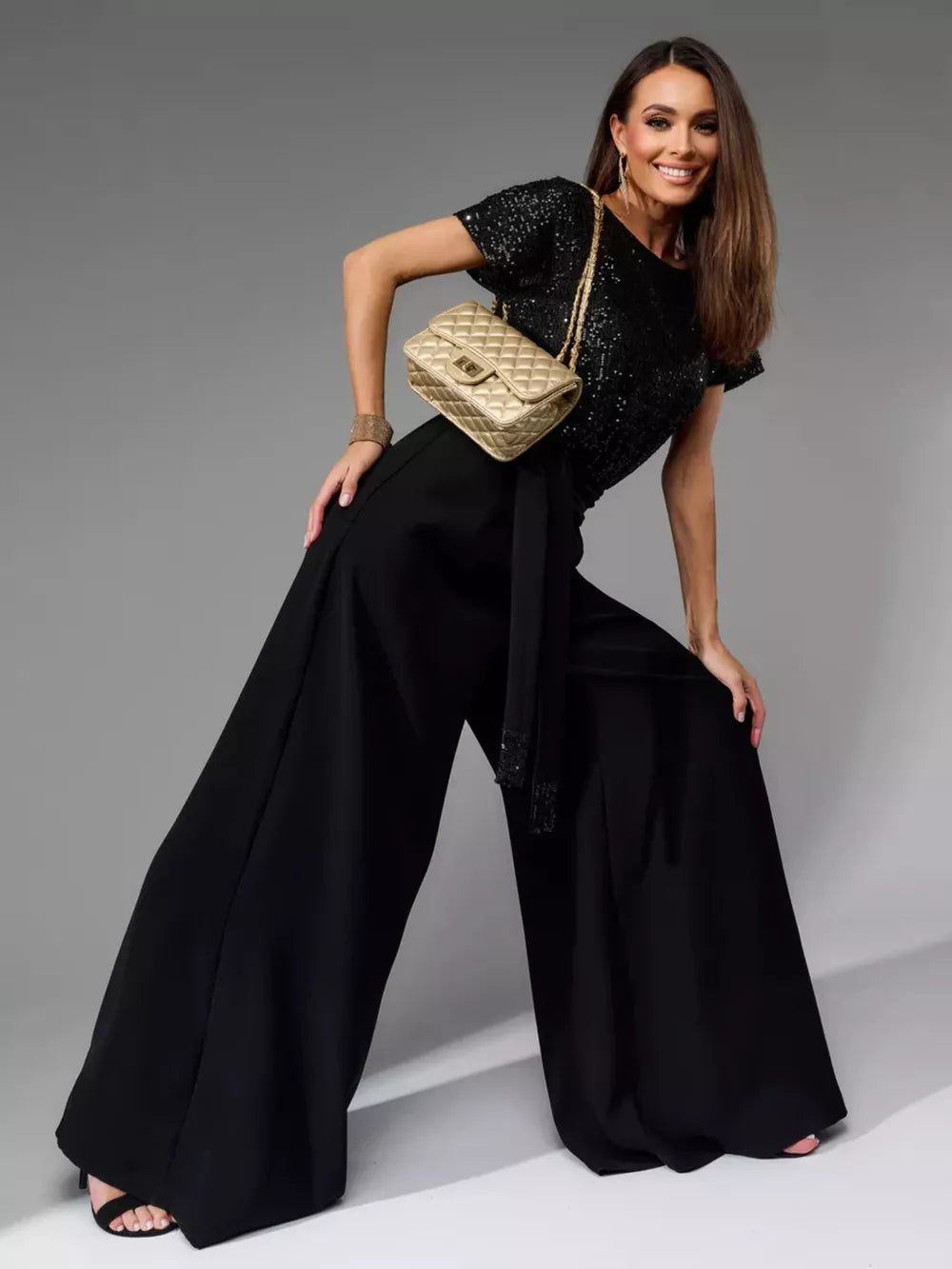Black sequin wide-leg jumpsuit with tie waist and embellished cuffs.