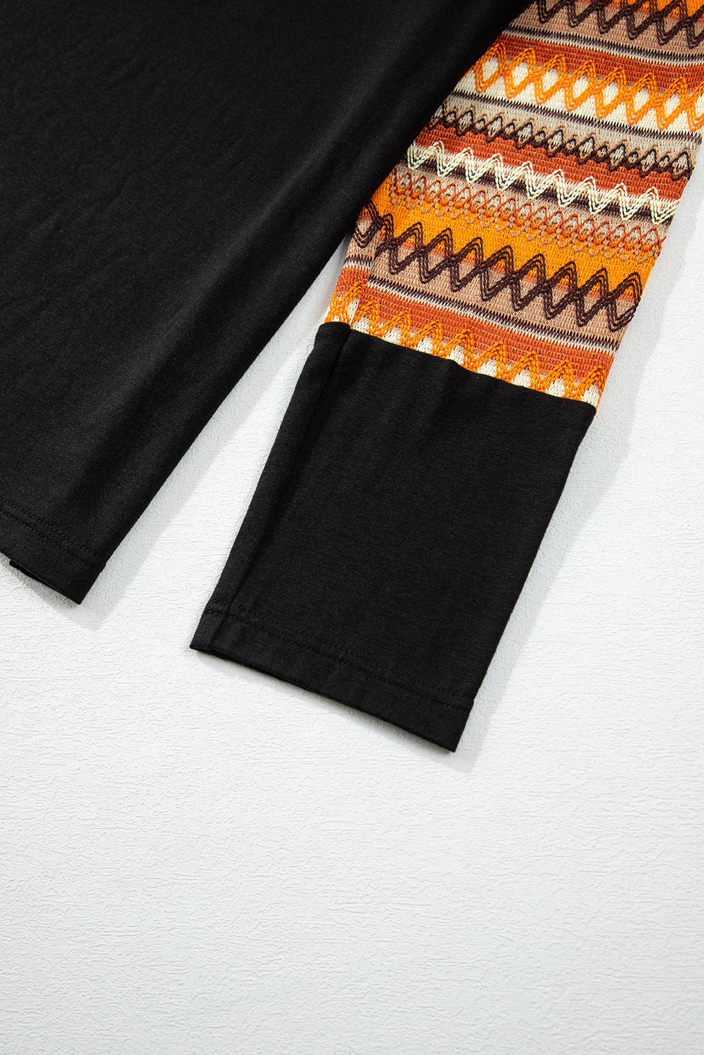 Black raglan tee with Aztec patterned sleeves in tangerine and brown.