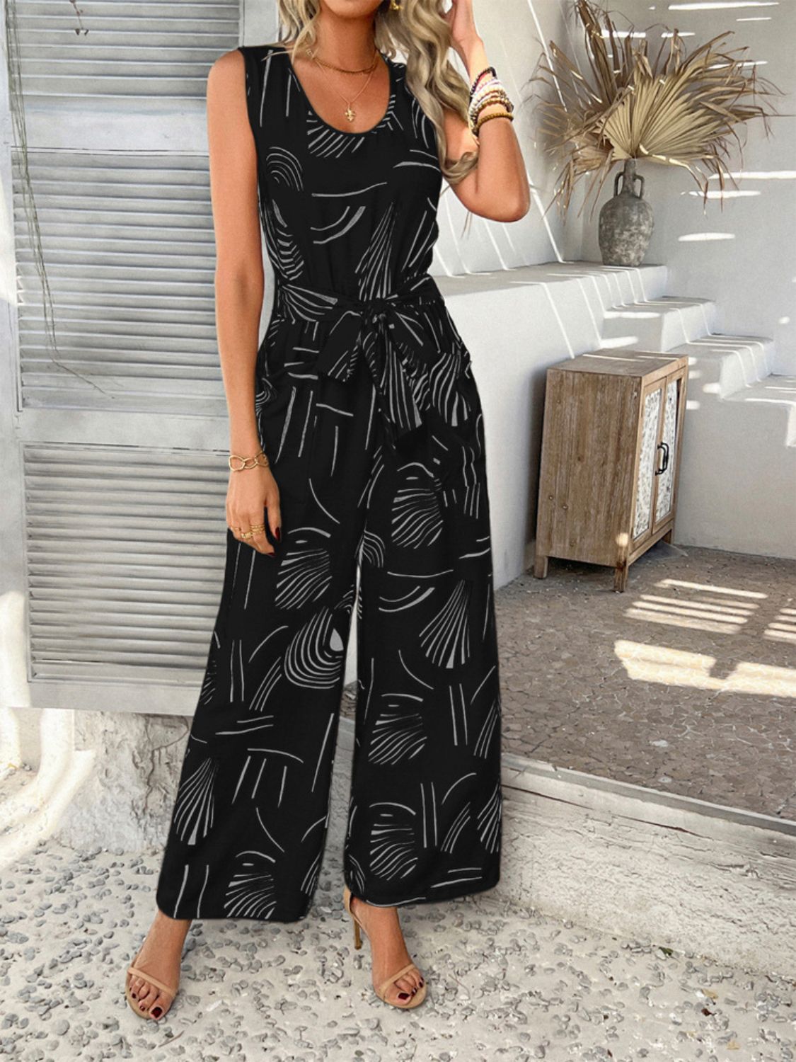 Black abstract print wide-leg jumpsuit with tie waist and scoop neck.