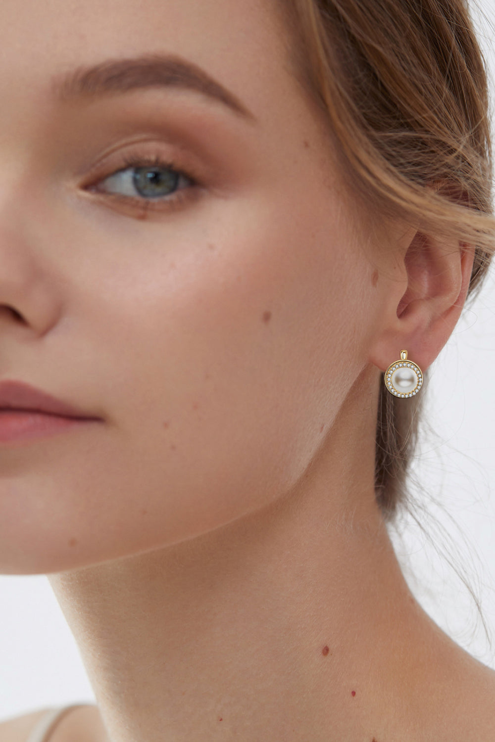 Gold pearl halo leverback earrings with crystal accents.