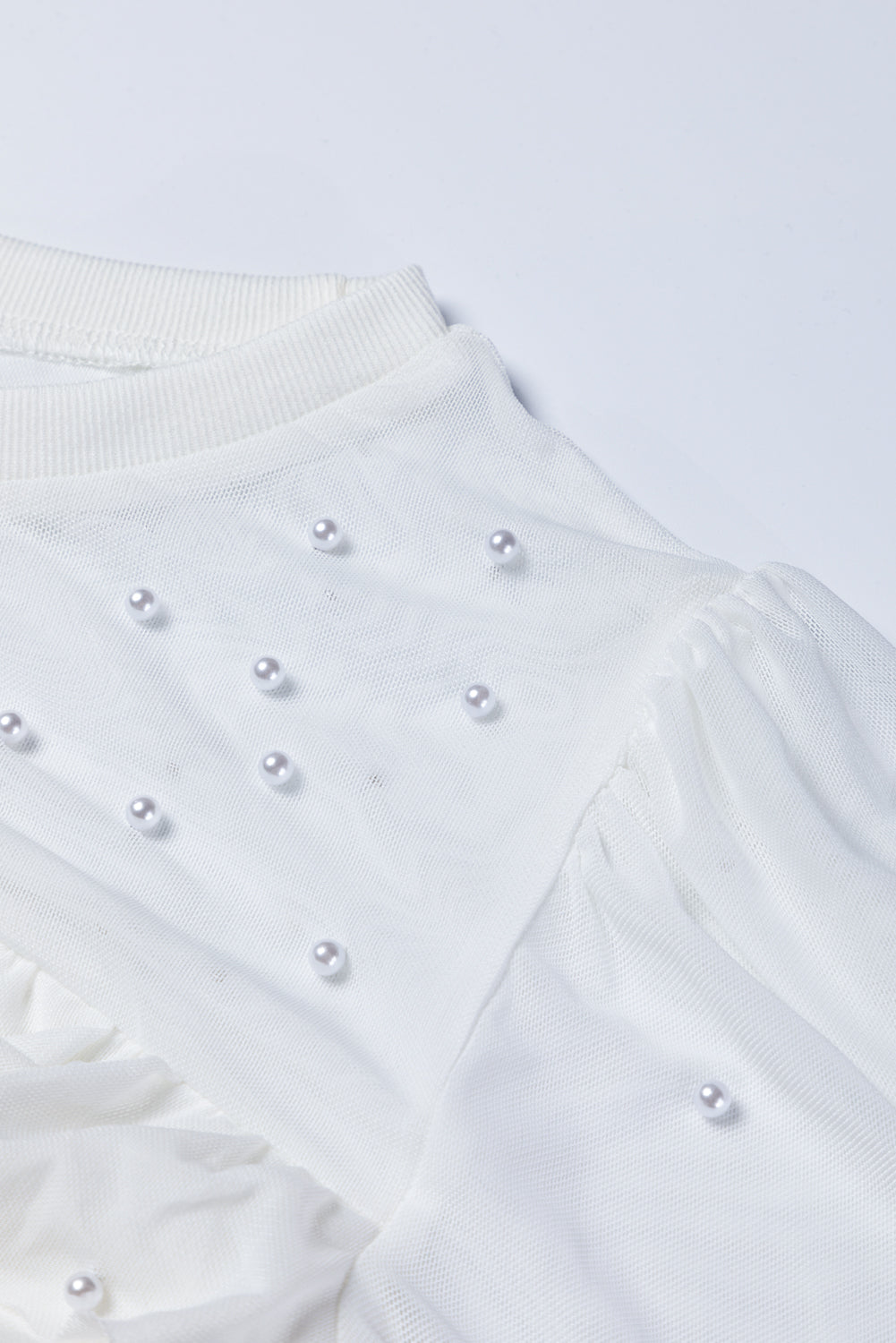 White mesh bodysuit with pearl embellishments and ruched detail
