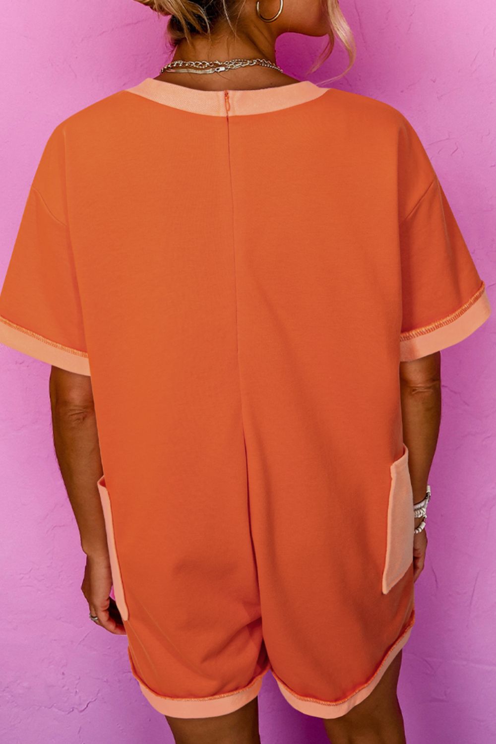Colorblock V-neck romper in orange with patch pockets and contrast trim.