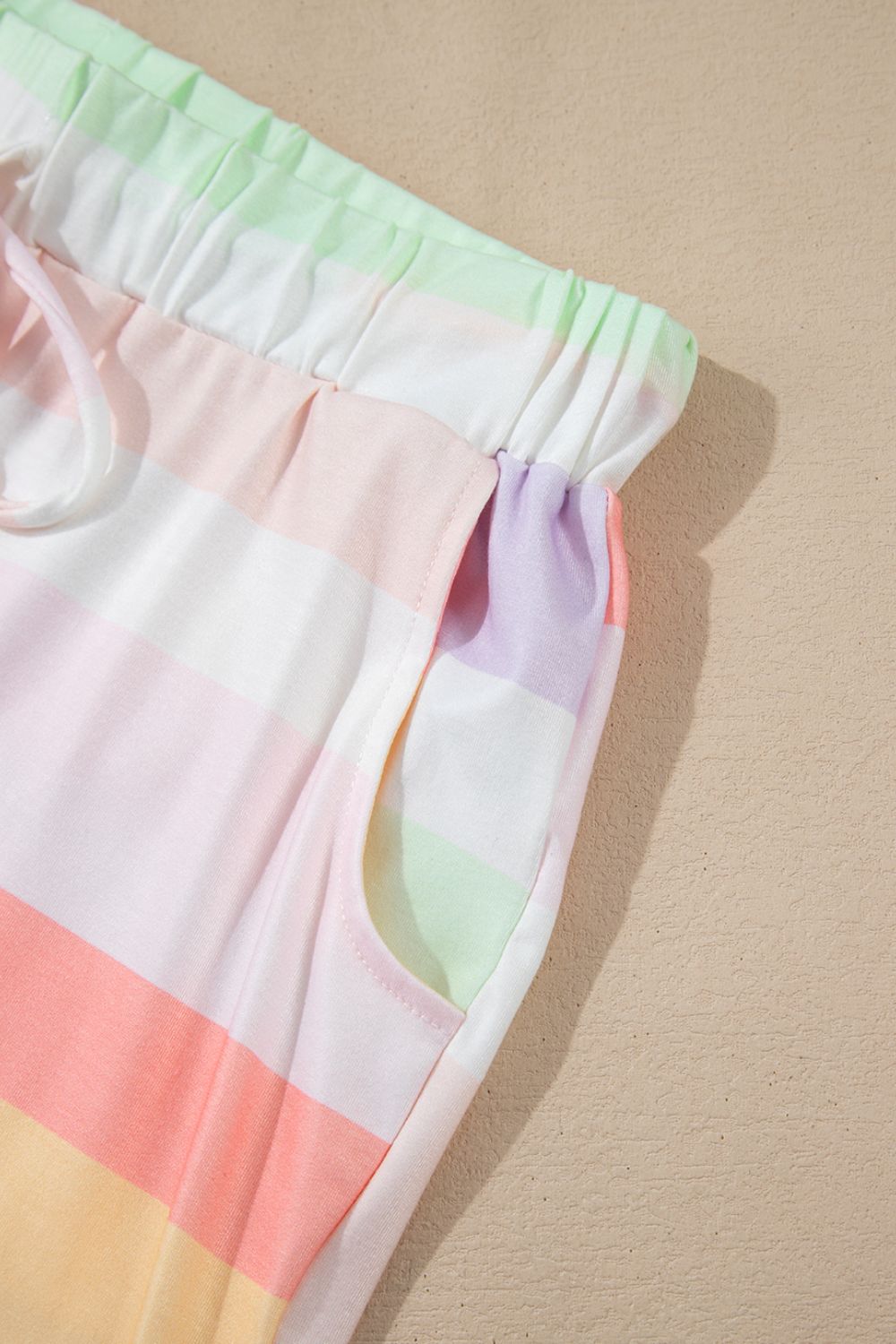 Loungewear pants with pastel rainbow stripes and a drawstring waist with pockets.