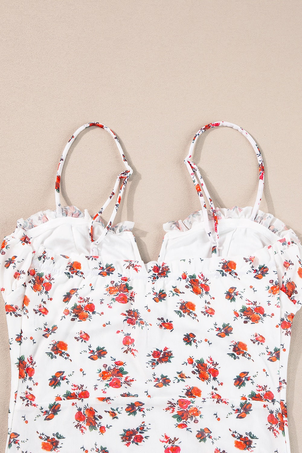 White floral bustier camisole with ruffle trim and adjustable straps.