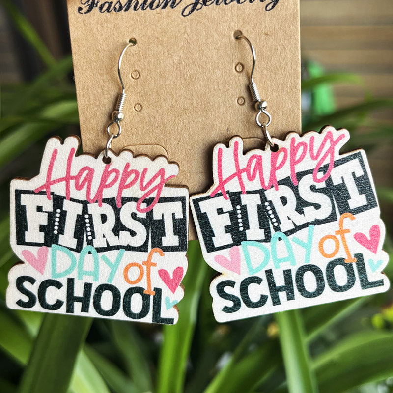 Graduation stacked book drop earrings with "Happy First Day of School" text and heart accents.