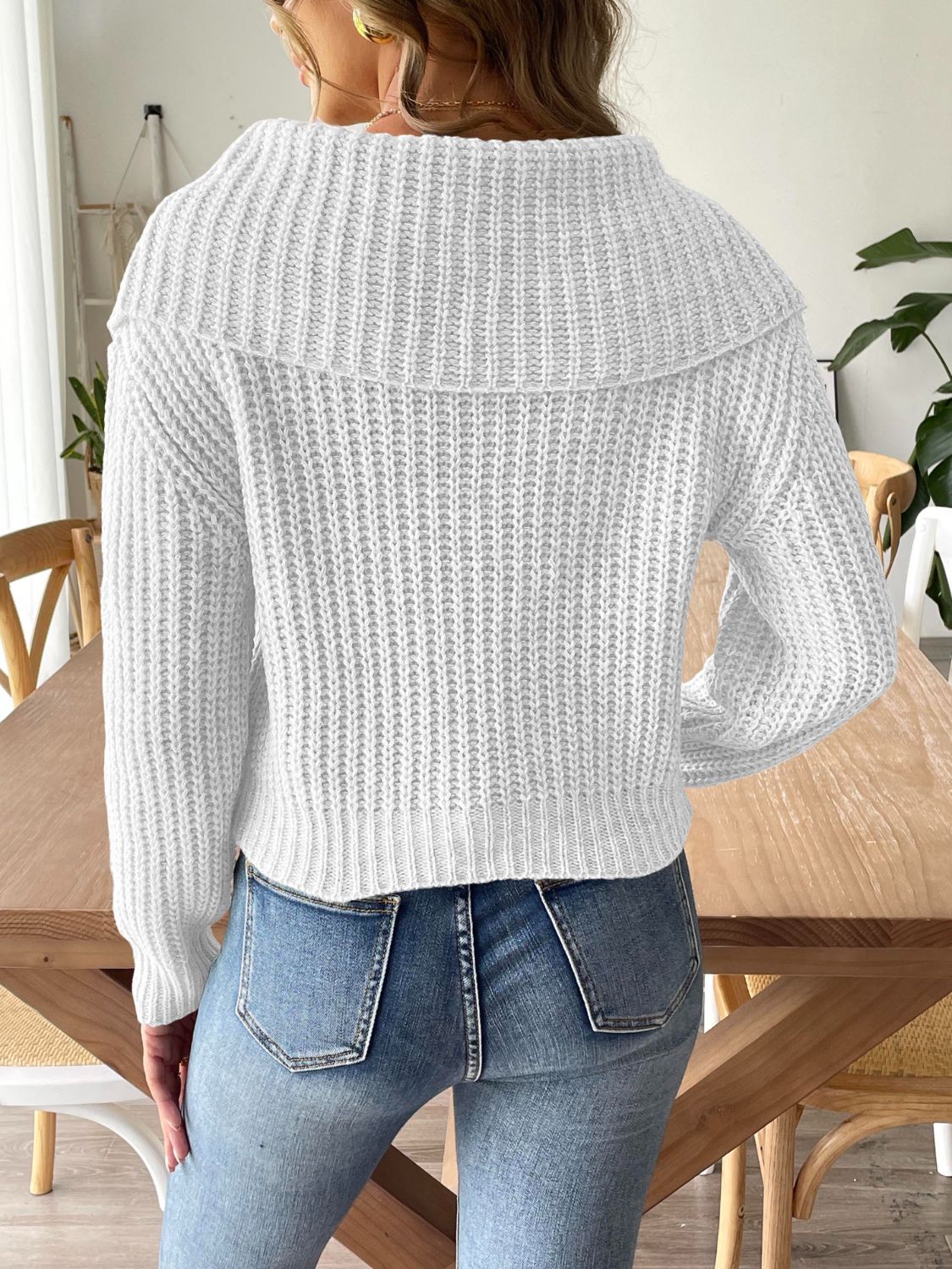 White ribbed knit sweater with shawl collar and long sleeves, styled with jeans.