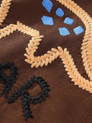 Dark brown sweatshirt with embroidered dinosaur details, wheat-like accents, and blue shapes.