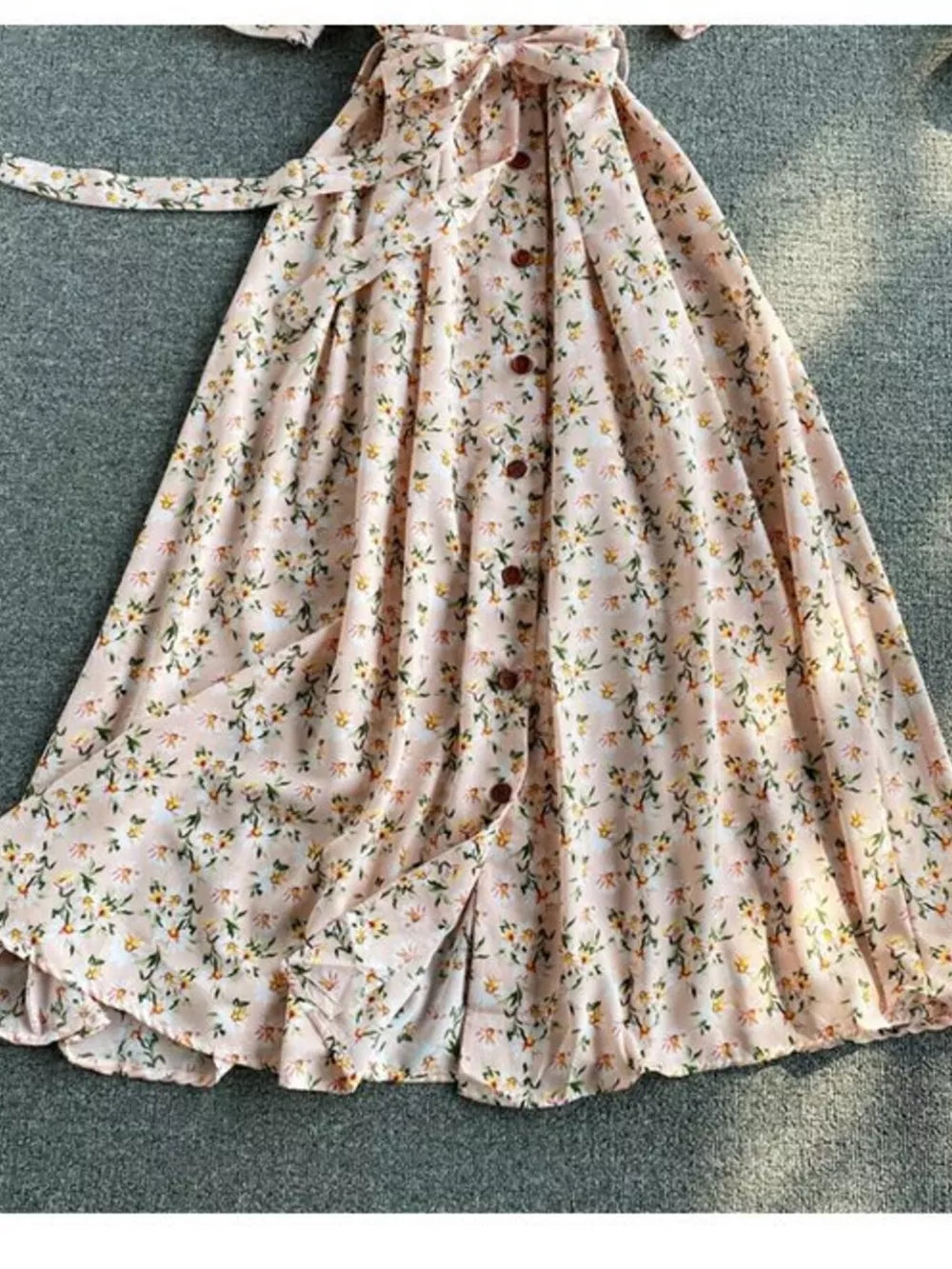 Pink floral midi dress with V-neck, button front, belted waist, and ruffled hem.
