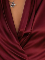 Wine red satin surplice blouse with draped neckline and geometric pendant necklace.