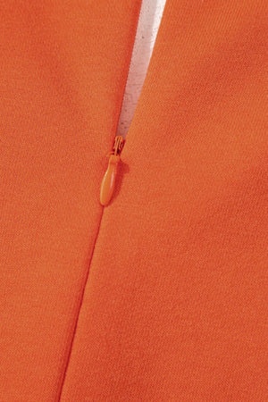 Orange colorblock romper with V-neck and patch pockets, close-up of zipper detail.