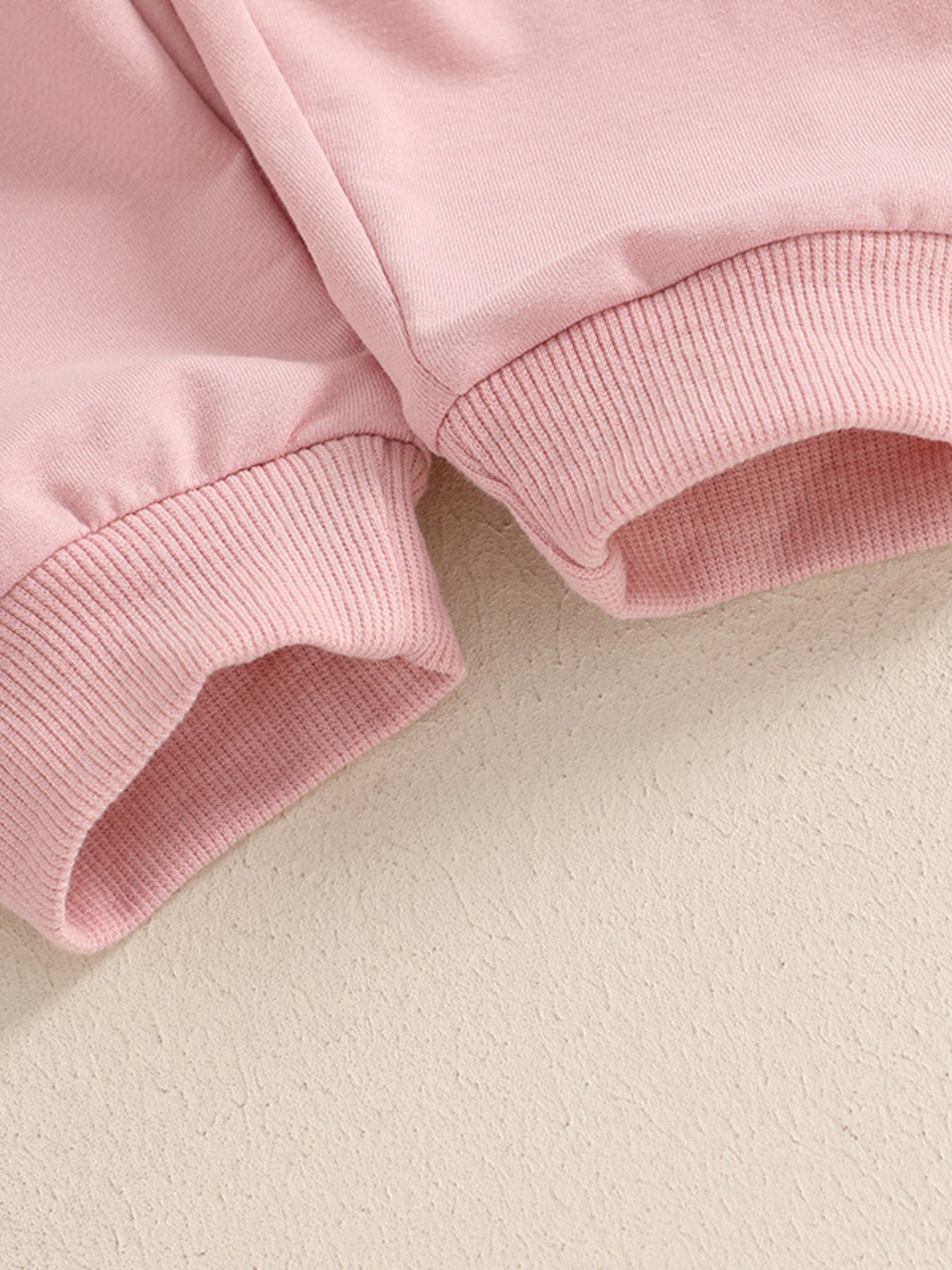 Pink cotton baby outfit set with ribbed cuffs and hem detail.