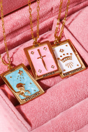 Tarot card pendant necklaces in light blue, blush pink, and white with gold chain and charms.