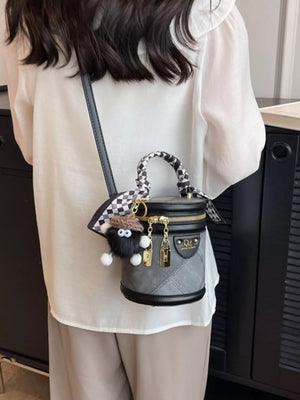 Quilted mini bucket bag in gray with checkered scarf detail and fuzzy charm.