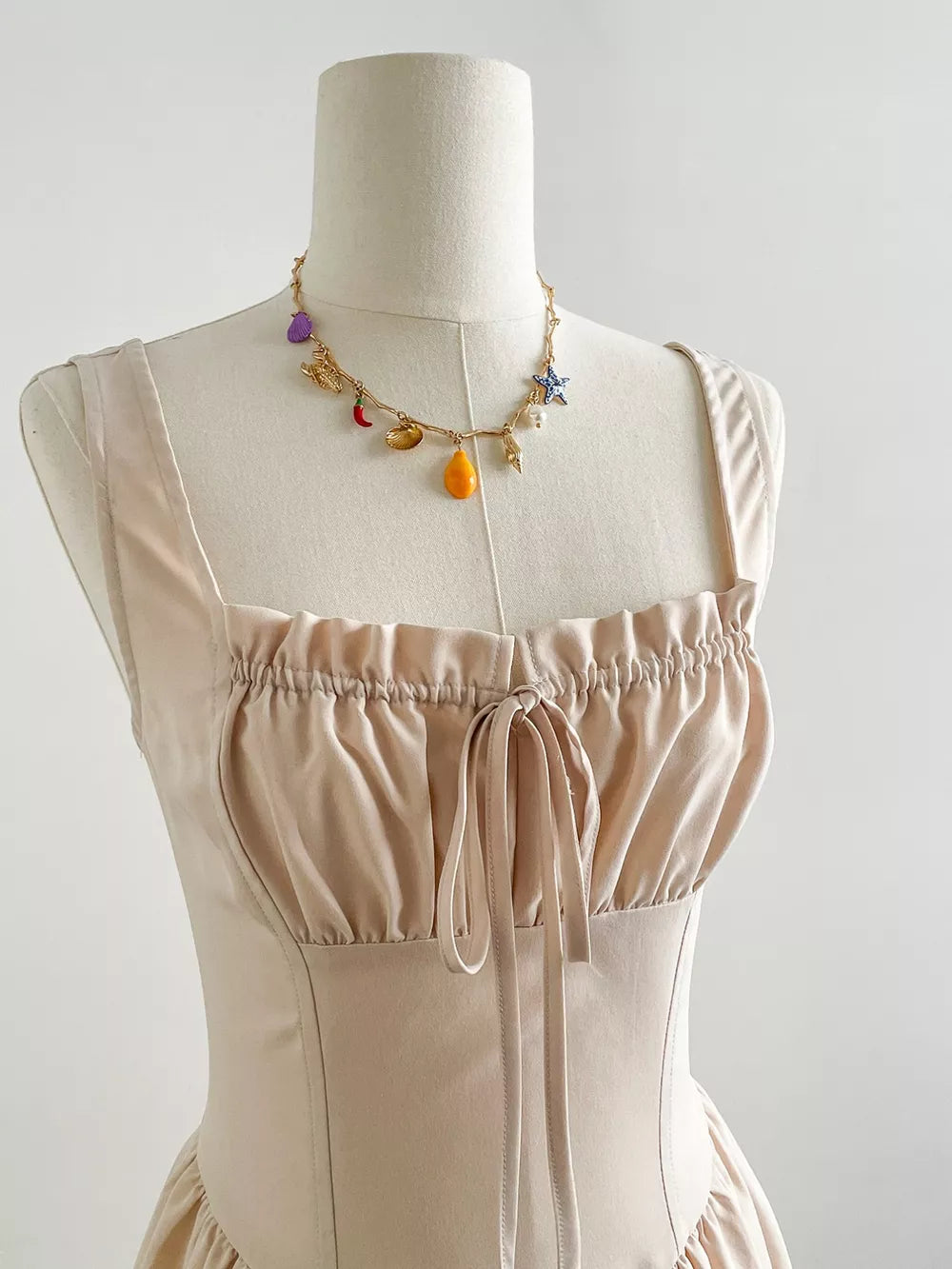 Elegant Square Neck A-line Maxi Dress in beige with ruched bodice and tie detail.