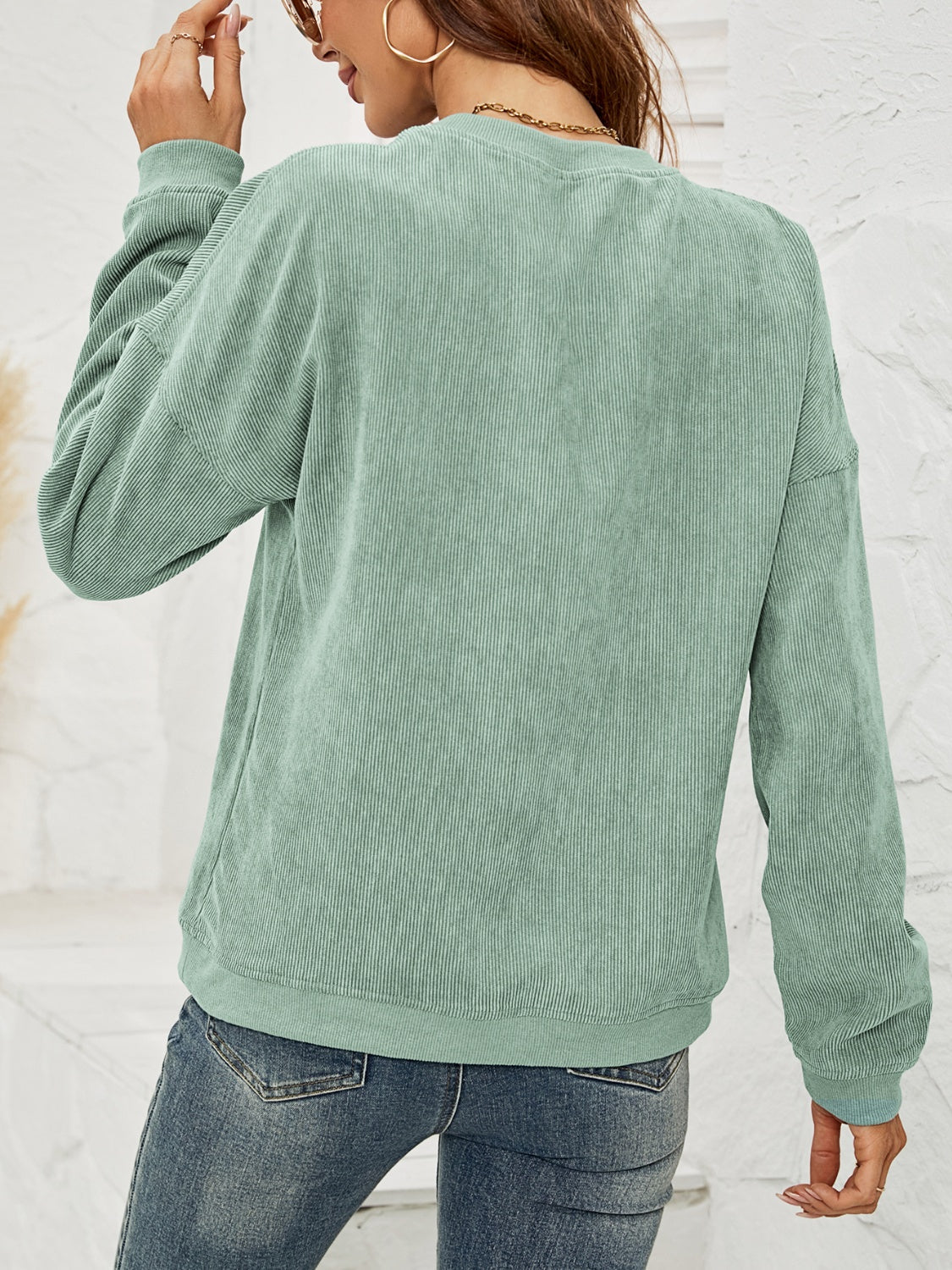 Sage corduroy sweatshirt with crewneck and long sleeves, textured fabric.