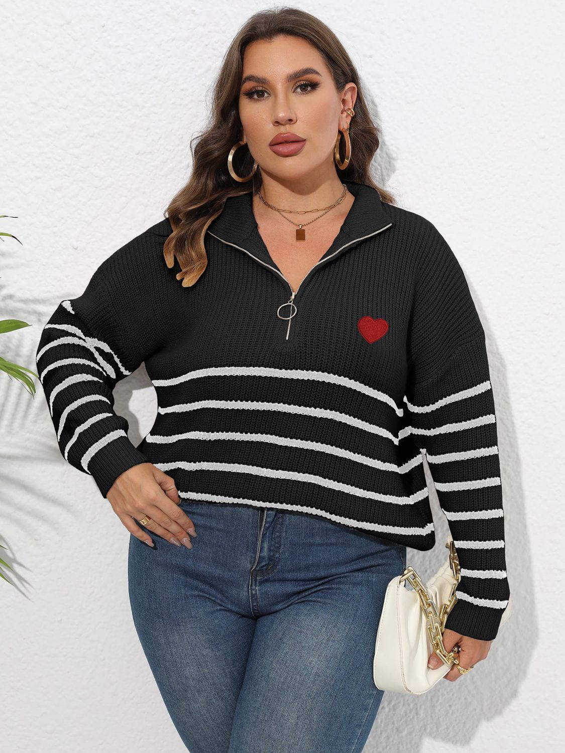 Black ribbed knit sweater with white stripes, quarter zip neckline, and red heart appliqué.