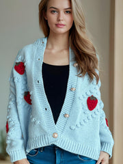 Pastel blue knit cardigan with red strawberry patches and pearl buttons.