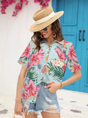 Tropical print camp collar shirt in sky blue with short sleeves and button front, styled with denim shorts.