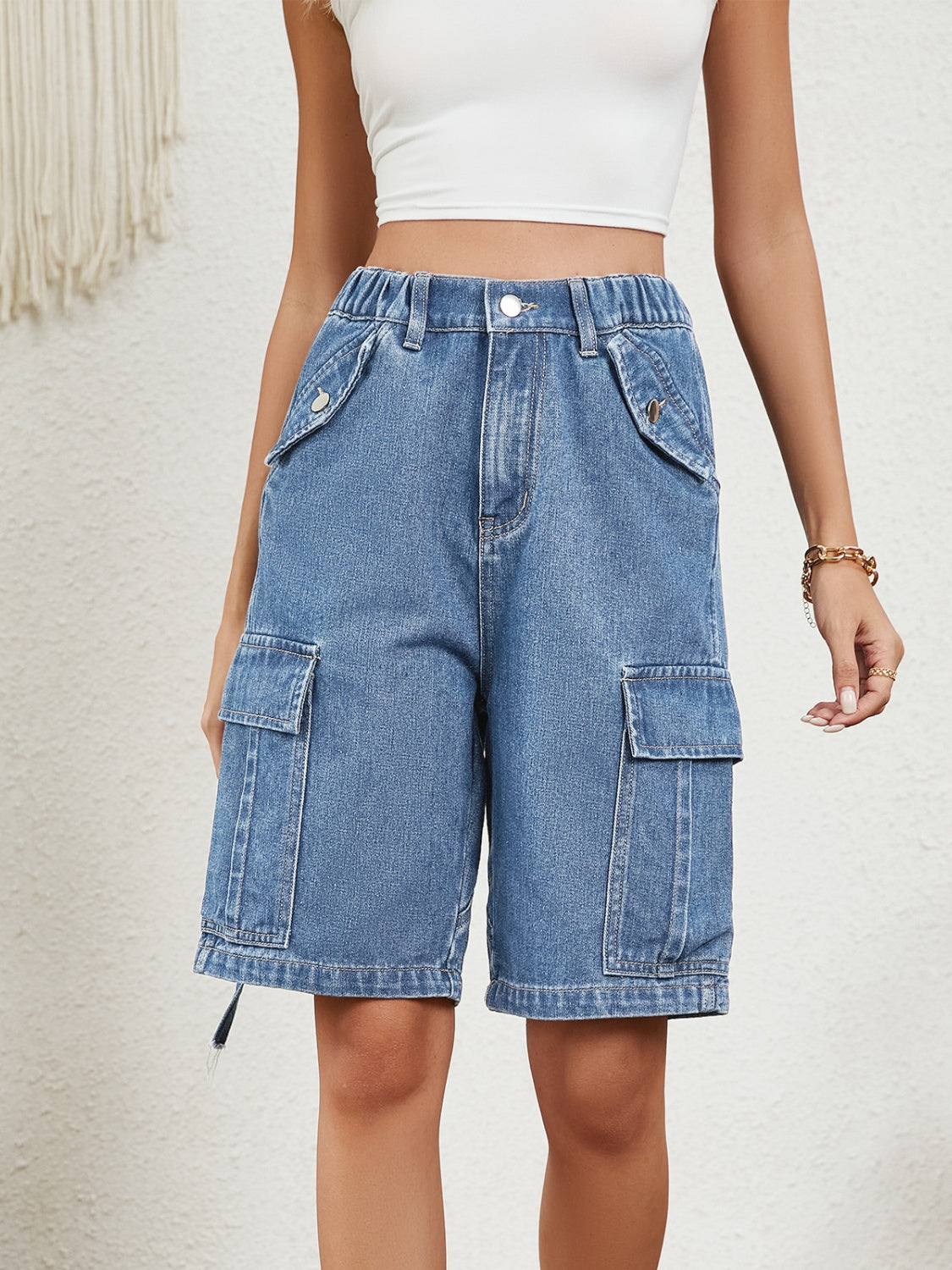 Denim bermuda shorts in medium wash with cargo pockets and drawstring hem