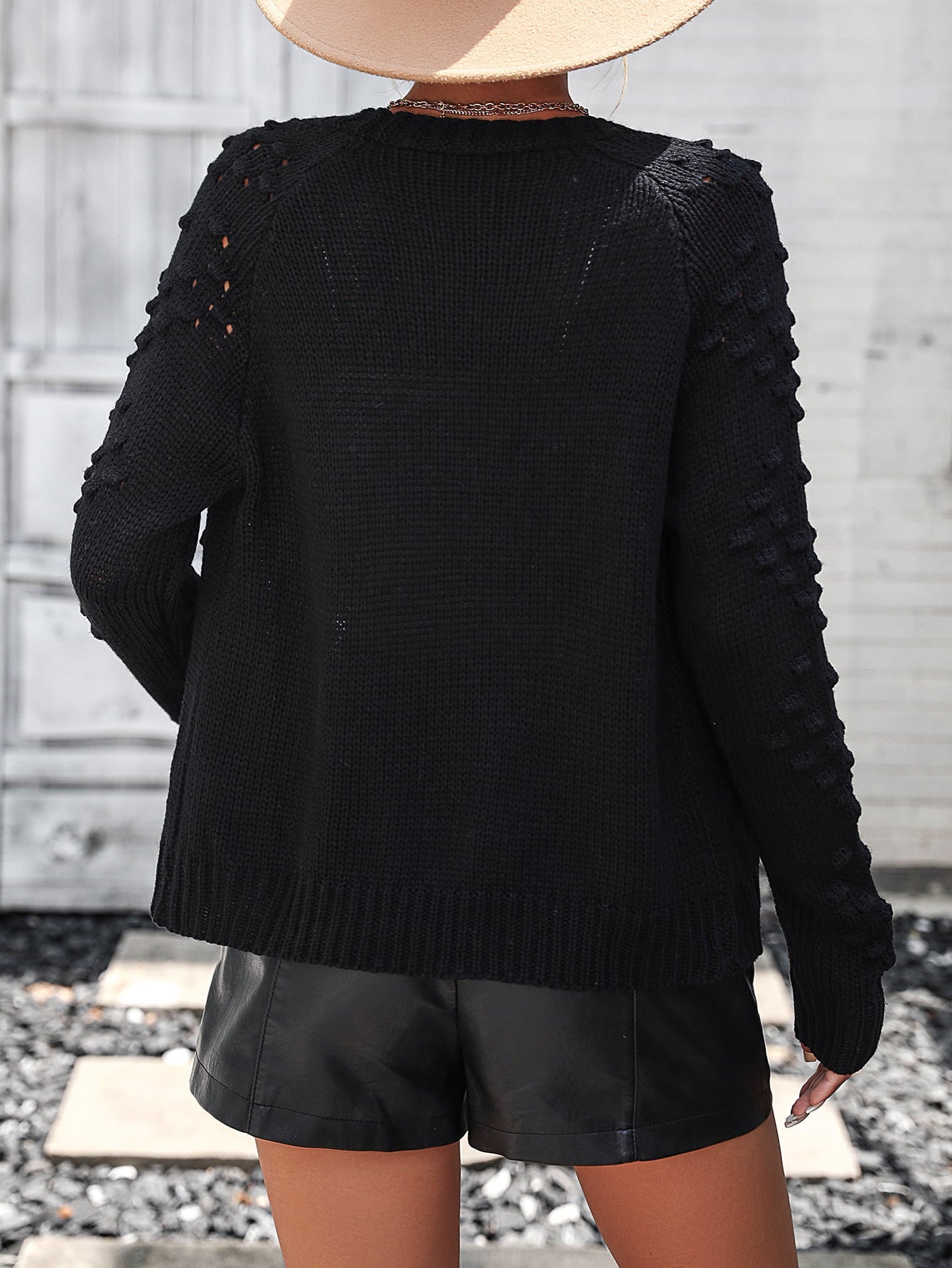Black acrylic cardigan with textured sleeves and open knit detail on shoulders.