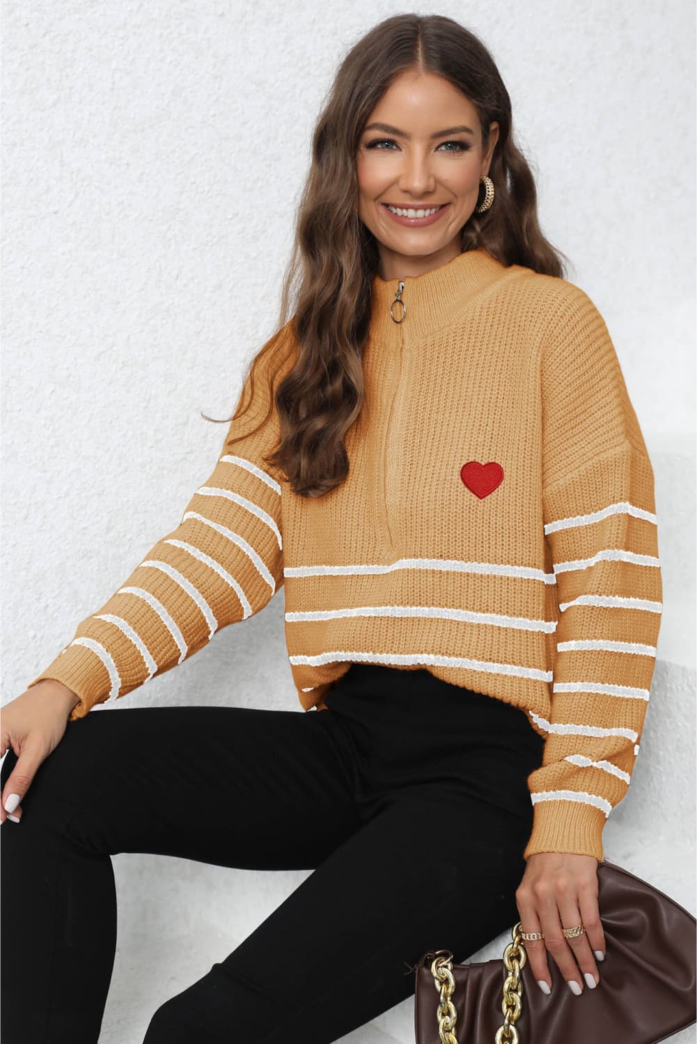 Tangerine knit sweater with zip neck, red heart patch, and white horizontal stripes on sleeves.