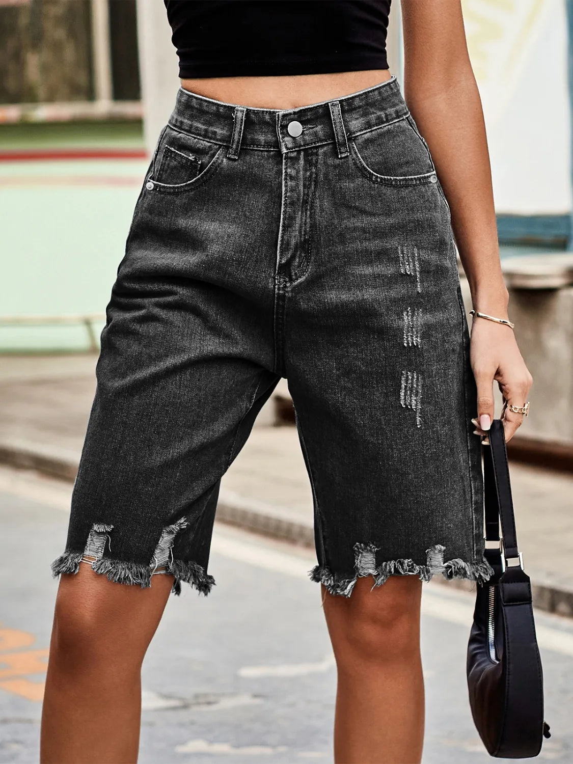Black distressed knee-length denim cutoff shorts with frayed hems.