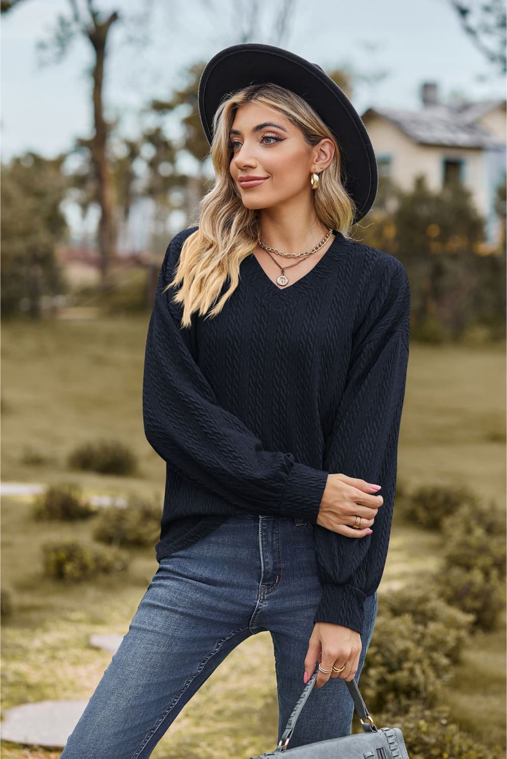 Dark blue textured cable knit V-neck sweater with long sleeves.