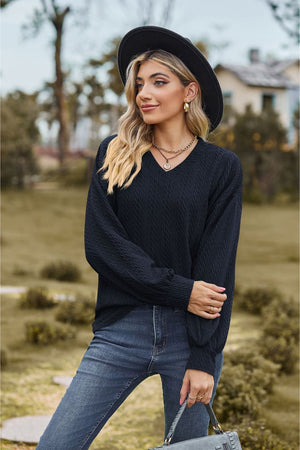 Dark blue textured cable knit V-neck sweater with long sleeves.