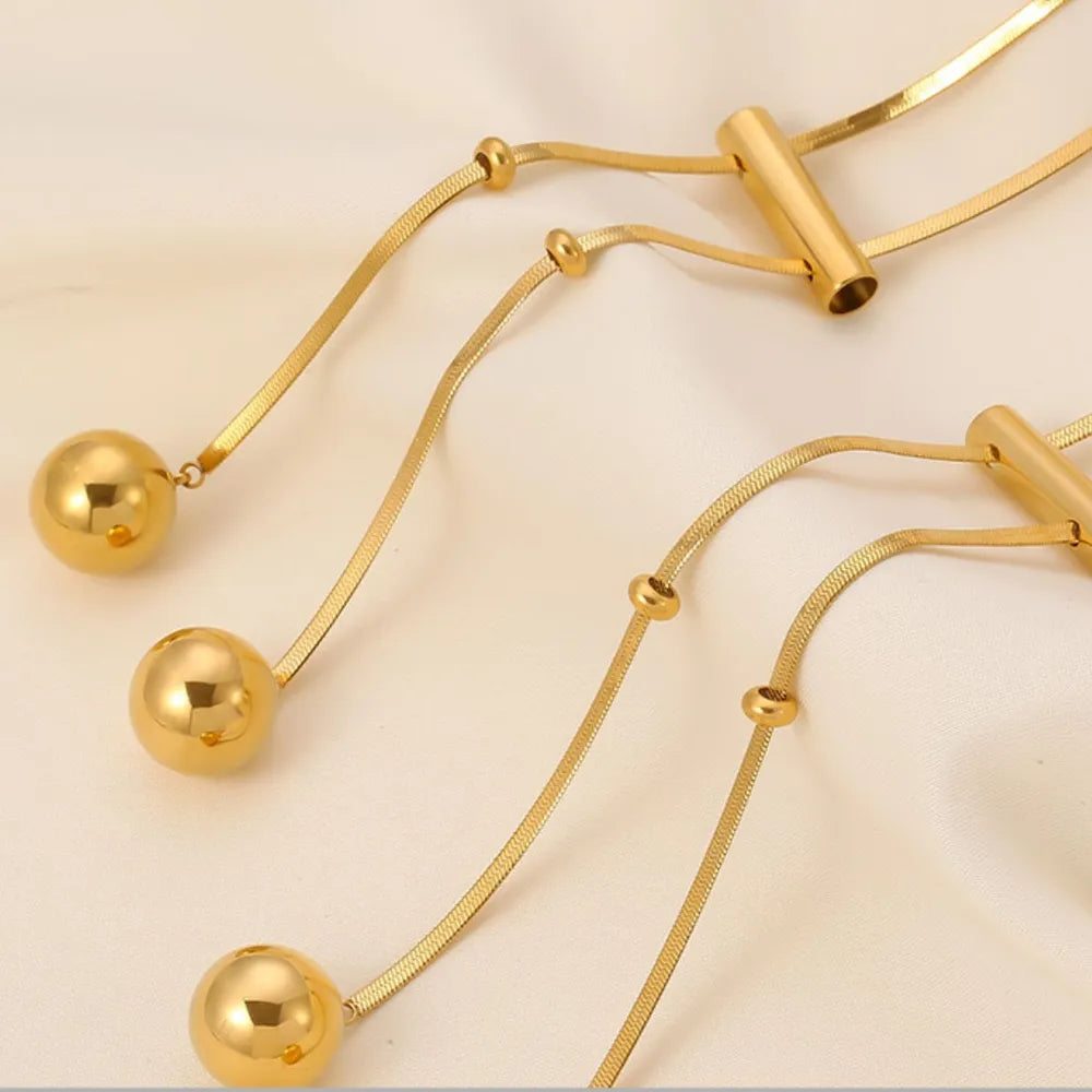 Gold lariat necklace with sphere drops and a bar detail, 18K gold-plated.