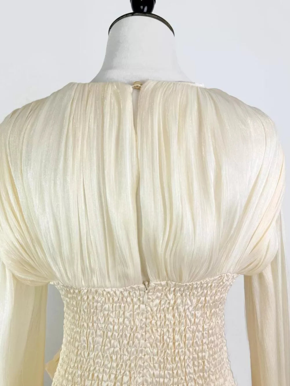 White ruffled mini dress with smocked corset waist detail and long sleeves.
